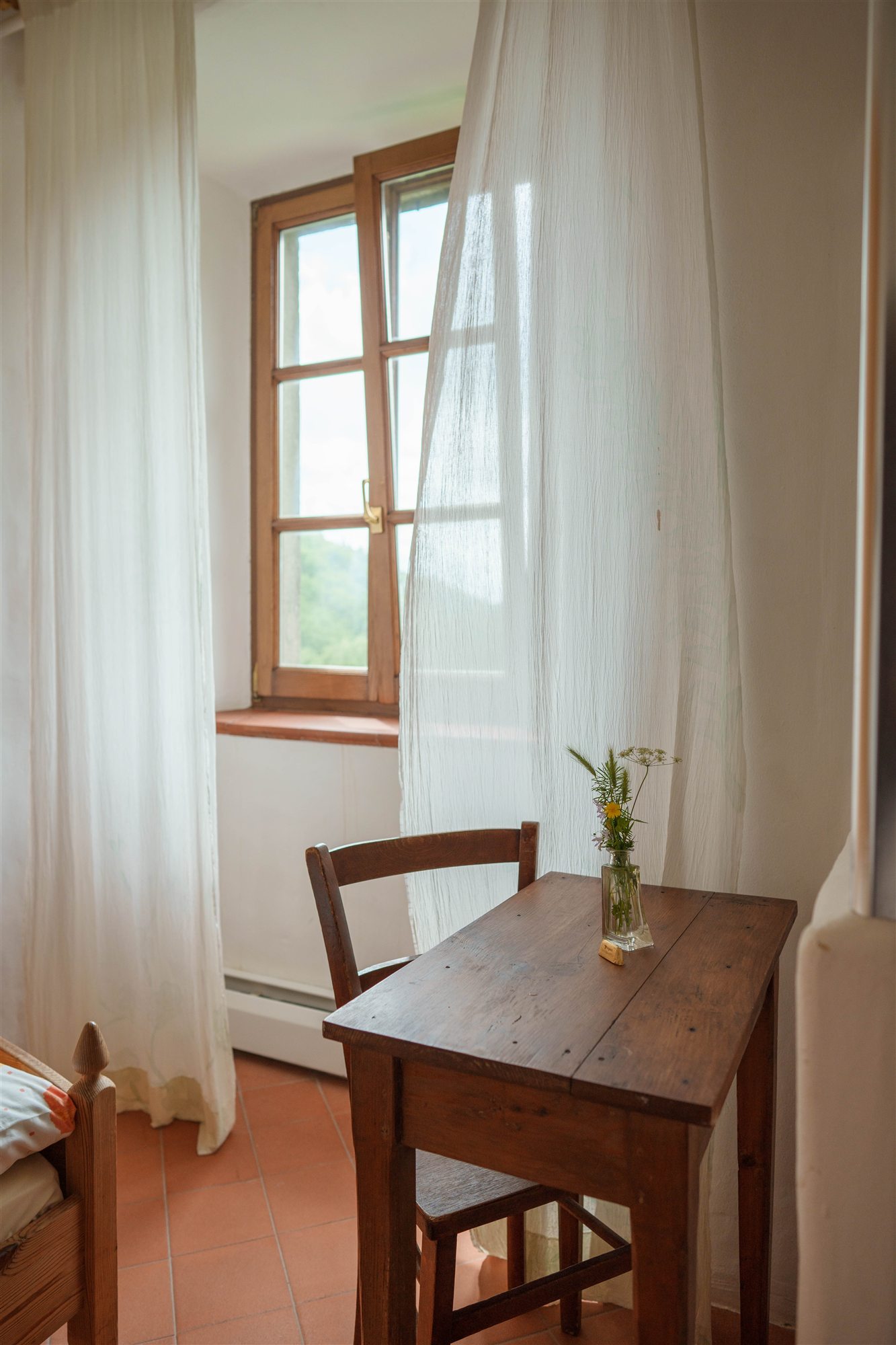 Ein schlichtes Zimmer mit Blumen und Blick zum Fenster.