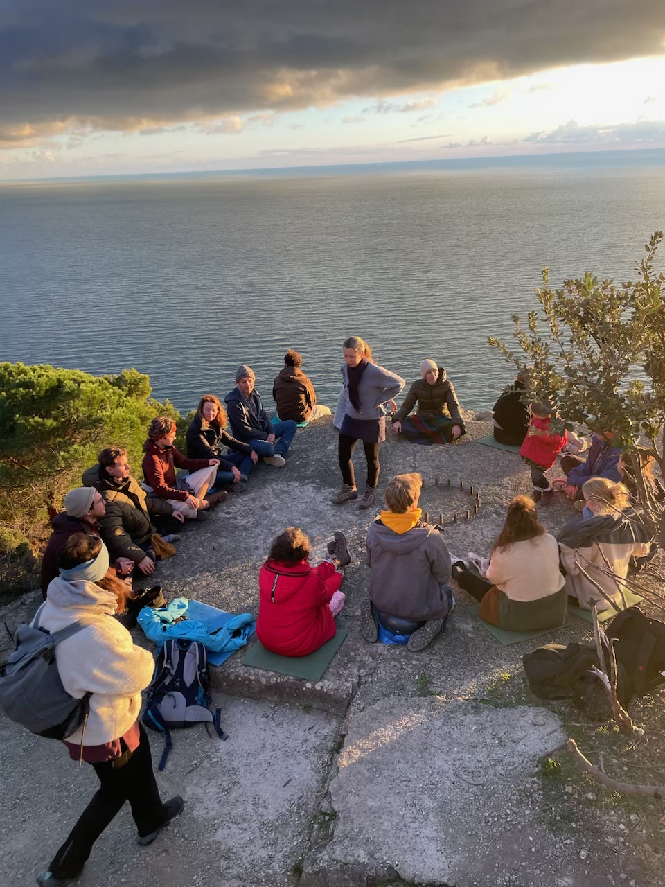 Die Retreat-Gruppe sitzt bei Abendlicht in einem Kreis hoch über dem Meer.